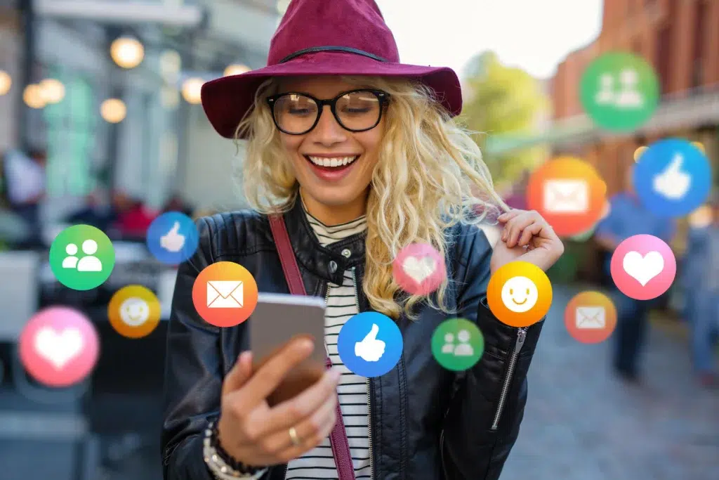 Uma pessoa no celular, Mulher sorridente usando smartphone rodeada de ícones de redes sociais, refletindo a interação digital.