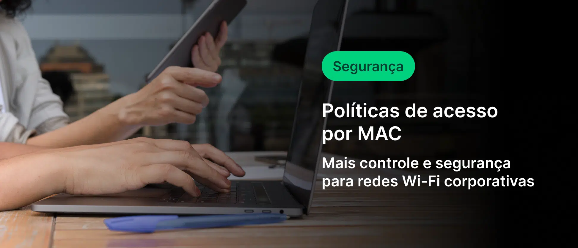 Pessoa utilizando laptop sobre mesa de madeira enquanto segura um tablet, em ambiente de escritório moderno. Na lateral direita, sobreposição escura com texto em português: “Segurança”, “Políticas de acesso por MAC” e “Mais controle e segurança para redes Wi-Fi corporativas”. Conceito de tecnologia, cibersegurança e gestão de acesso em redes corporativas.