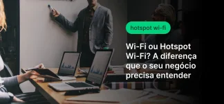 Imagem de pessoas em uma reunião de negócios usando notebooks e celulares em um ambiente corporativo, com texto sobre Wi‑Fi ou Hotspot e a diferença para o seu negócio.