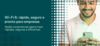 Mão usando smartphone e notebook com ícones de Wi‑Fi e sinal verde, mostrando o tema “Wi‑Fi 6” e destacando vantagens para redes corporativas em um layout de comunicação digital.