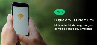 Pessoa segurando um smartphone com um símbolo de Wi-Fi na tela, ao fundo um ambiente ao ar livre. Texto na imagem explica os benefícios do Wi-Fi Premium, como maior velocidade, segurança e controle do ambiente.